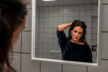 woman looks at her reflection in the mirror