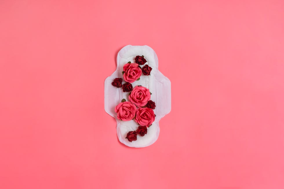 white sanitary pad with red and pink flowers on it, woman health or body positive concept pink background flatlay copyspace