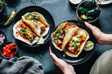 person holding a plate of vegan tacos