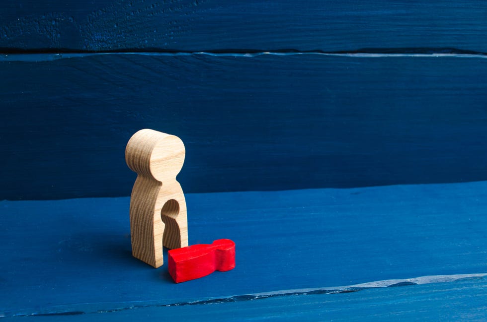 a wooden figure of a woman with a void from which a red child fellthe concept of the loss of a child, abortion of pregnancy, miscarriage mother lost her childdeprivation of parental rights