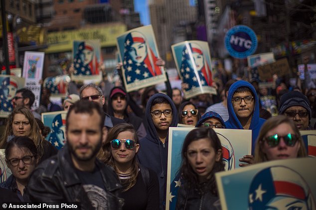 People carry posters during a rally in support of Muslim Americans and protest of President Donald Trump's immigration policies in Times Square, New York, on Sunday