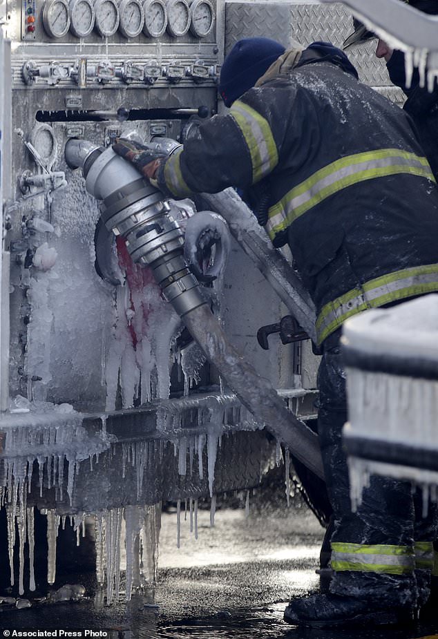 FILE - In this Jan. 5, 2018, file photo, a Newark firefighter labors through ice while disconnecting hoses off an engine after helping battle a five building fire in Newark, N.J. Firefighters battling blazes in the extreme cold are faced with treacherous conditions, frozen hydrants and slick surfaces that make an already difficult job even harder. Departments in colder climates prepare months ahead for the coming freeze, readying equipment and changing how they approach fires in the coldest months. (AP Photo/Julio Cortez, File)