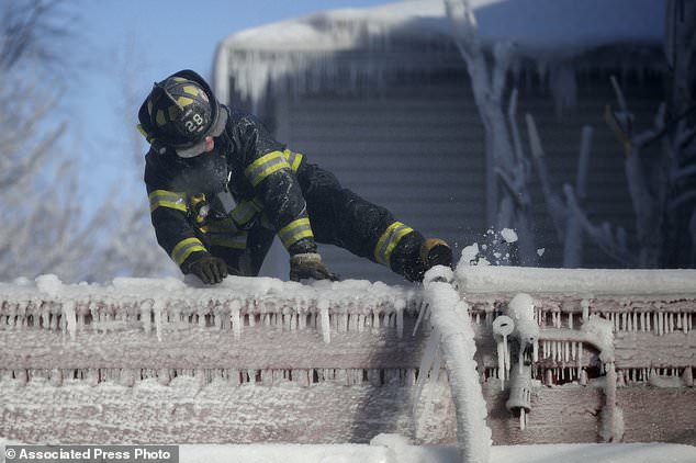 FILE- In this Jan. 5, 2018, file photo, a Newark firefighter kicks free a hose frozen onto a roof of a building after helping battle a five building fire in Newark, N.J. Firefighters battling blazes in the extreme cold are faced with treacherous conditions, frozen hydrants and slick surfaces that make an already difficult job even harder. Departments in colder climates prepare months ahead for the coming freeze, readying equipment and changing how they approach fires in the coldest months. (AP Photo/Julio Cortez, File)