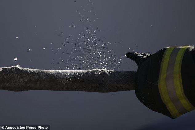 FILE- In this Jan. 5, 2018, file photo, ice breaks away from a hose as a Newark firefighter pulls it onto an engine after helping battle a five building fire in Newark, N.J. Firefighters battling blazes in the extreme cold are faced with treacherous conditions, frozen hydrants and slick surfaces that make an already difficult job even harder. Departments in colder climates prepare months ahead for the coming freeze, readying equipment and changing how they approach fires in the coldest months. (AP Photo/Julio Cortez, File)