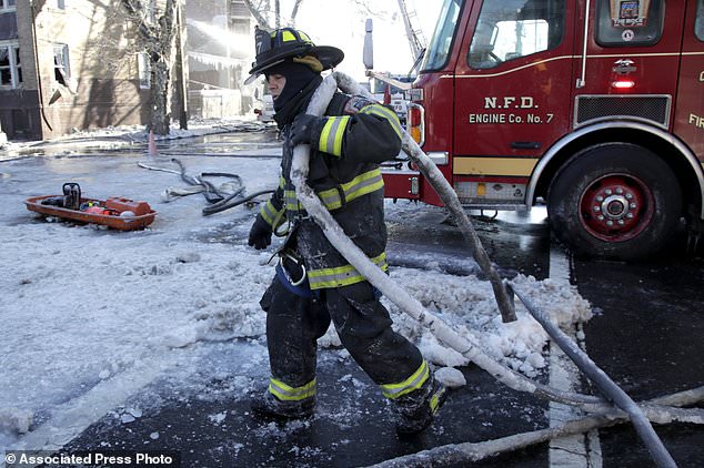 FILE- In this Jan. 5, 2018 file photo, a Newark firefighter pulls a hose back onto an engine after helping battle a five building fire in Newark, N.J. Firefighters battling blazes in the extreme cold are faced with treacherous conditions, frozen hydrants and slick surfaces that make an already difficult job even harder. Departments in colder climates prepare months ahead for the coming freeze, readying equipment and changing how they approach fires in the coldest months. (AP Photo/Julio Cortez, File)