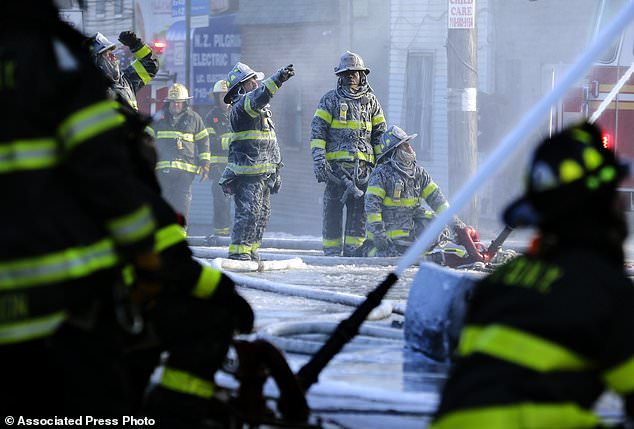 FILE- In this Jan. 2, 2018, file photo, firefighters are covered with ice from water sprayed from their hoses as they work to contain a fire in the Bronx section of New York. Firefighters battling blazes in the extreme cold are faced with treacherous conditions that can slow them down when every second counts. (AP Photo/Seth Wenig, File)