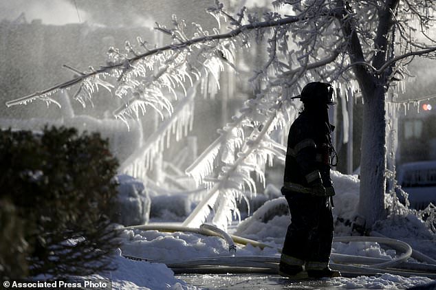 FILE- In this Jan. 5, 2018, file photo, a Newark firefighter walks near the site of a fire in Newark, N.J. Firefighters battling blazes in the extreme cold are faced with treacherous conditions that can slow them down when every second counts.  (AP Photo/Julio Cortez, File)