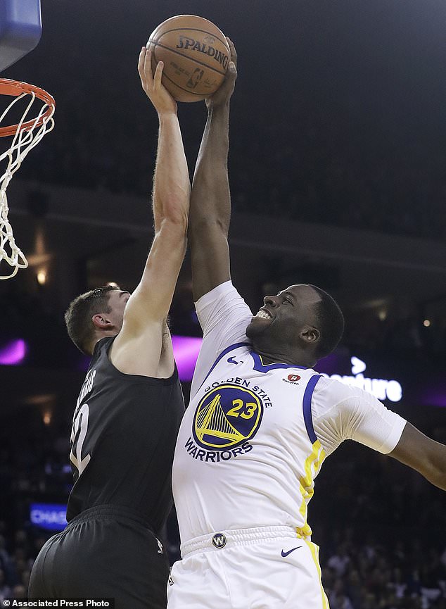 Brooklyn Nets forward Joe Harris, left, blocks a shot by Golden State Warriors forward Draymond Green (23) during the first half of an NBA basketball game in Oakland, Calif., Tuesday, March 6, 2018. (AP Photo/Jeff Chiu)