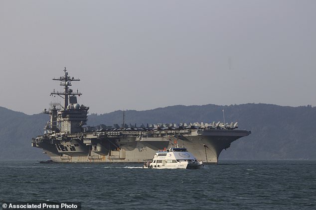 A Vietnamese passenger boat sails past U.S aircraft carrier USS Carl Vinson as it docks in Danang bay, Vietnam on Monday, March 5, 2018. For the first time since the Vietnam War, a U.S. Navy aircraft carrier is paying a visit to a Vietnamese port, seeking to bolster both countries' efforts to stem expansionism by China in the South China Sea. (AP Photo/ Hau Dinh)