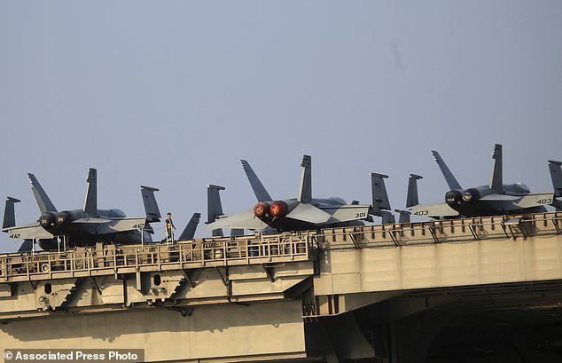 An American navy officer walks aboard the aircraft carrier USS Carl Vinson as it docks in Danang bay Vietnam on Monday, March 5, 2018. For the first time since the Vietnam War, a U.S. Navy aircraft carrier is paying a visit to a Vietnamese port, seeking to bolster both countries' efforts to stem expansionism by China in the South China Sea. (AP Photo/ Hau Dinh)