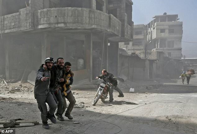 Volunteers from the Syrian Civil Defence help a man in Hamouria during Syrian government shelling on rebel-held areas in the Eastern Ghouta region on the outskirts of Damascus on March 6, 2018