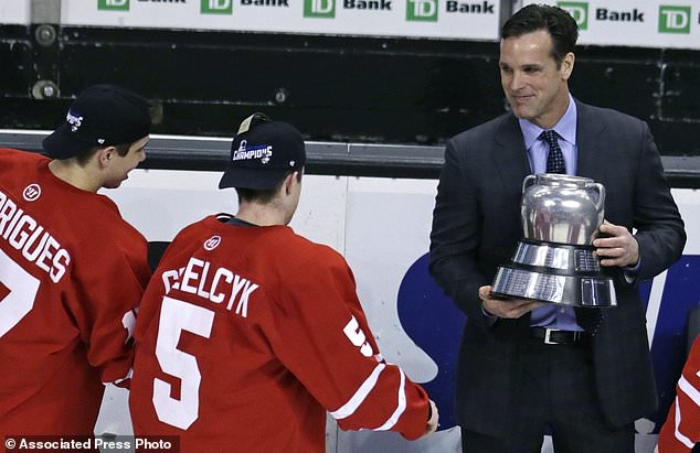 FILE - In this Feb. 23, 2015, file photo, Boston University hockey head coach David Quinn, right, hands the Beanpot trophy to Matt Grzelcyk (5) and Evan Rodrigues, left, after their overtime win against Northeastern in Boston. The New York Rangers have hired Boston University's David Quinn as their new head coach. General manager Jeff Gorton announced the long-reported move Wednesday, May 23, 2018. (AP Photo/Charles Krupa, File)