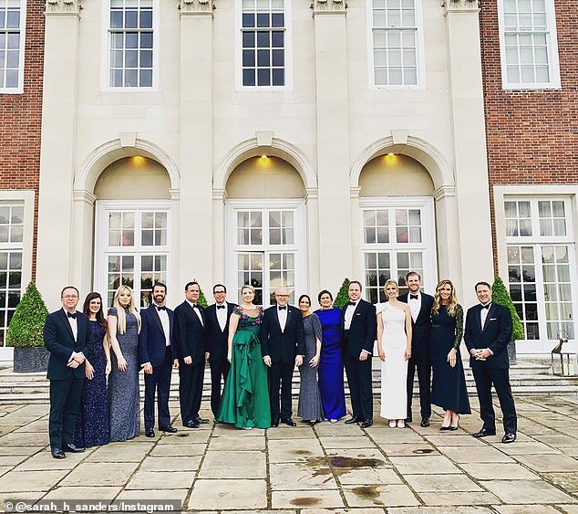 The entire group smiles for a photo in their fancy dresses and suits outside