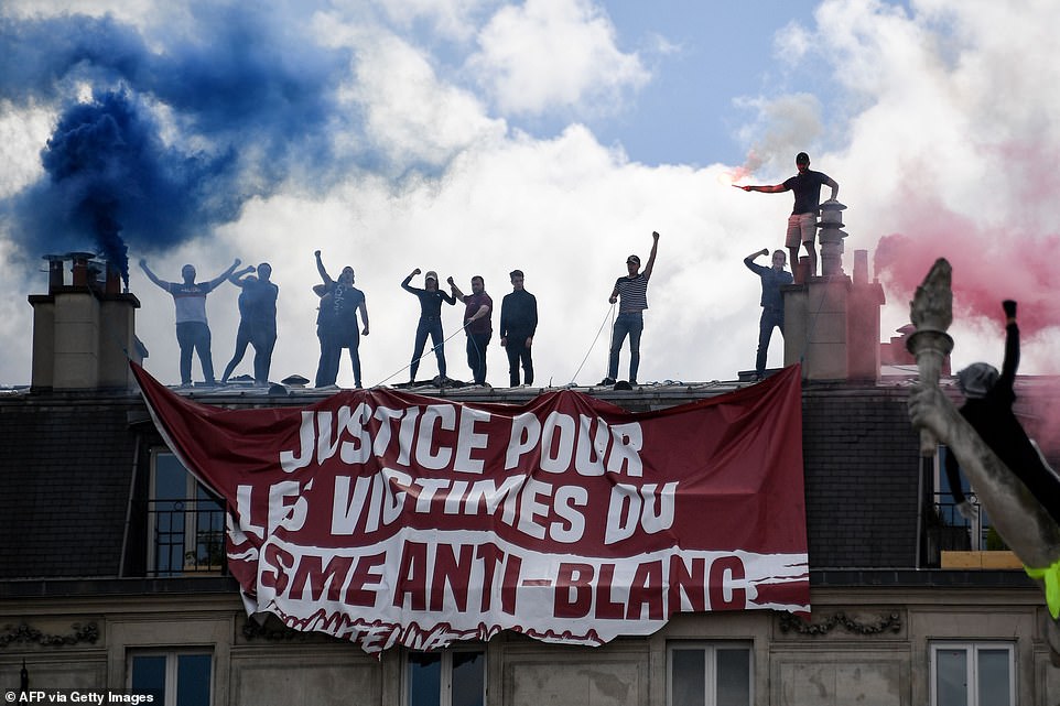 Members of far right group Generation Identitaire gesture after deploying a banner on Saturday, cut by residents who tried to remove it, and reading 'victims of anti-white racism'