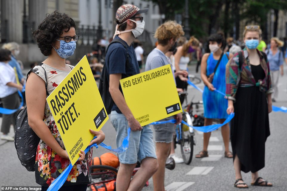 A protester holds a poster that reads 'racism kills' as she takes part in a Black Lives Matter demonstration in Berlin