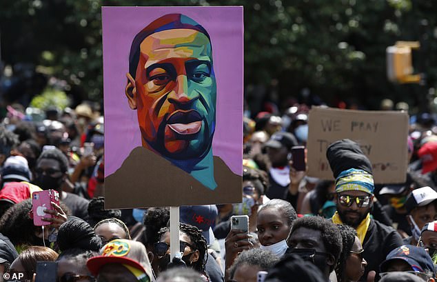 In New York City, a protester on Sunday held aloft a tribute to George Floyd, killed on May 25