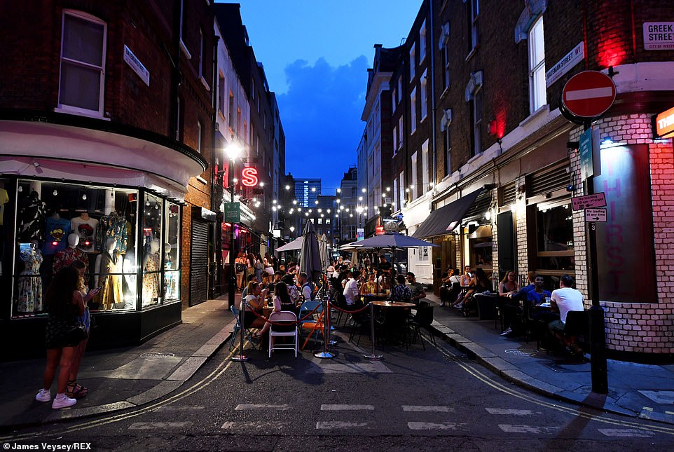 People enjoy a meal on Bateman Street in London's Soho yesterday evening as the Eat Out to Help Out scheme continues