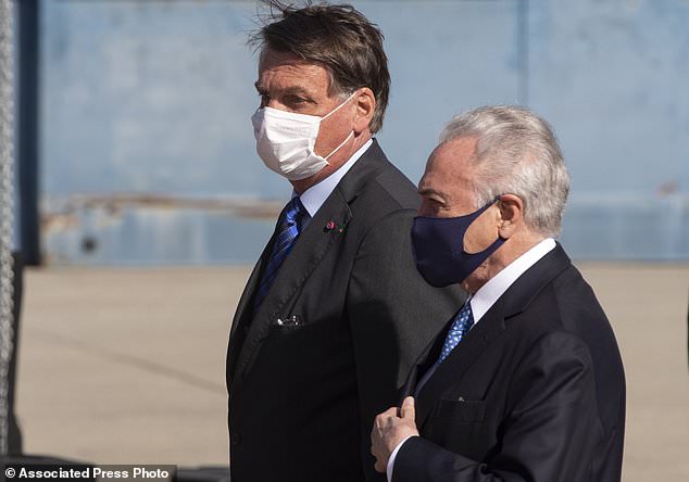 Brazilian President Jair Bolsonaro, left, and former President Michel Temer attend a ceremony to send off a planeload of humanitarian aid to Lebanon, including medical supplies and experts to assist in the wake of the explosion in Beirut, at the Air Force base in Guarulhos, greater Sao Paulo area, Brazil, Wednesday, Aug. 12, 2020. (AP Photo/Andre Penner)