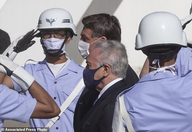 Brazilian President Jair Bolsonaro, behind center, and former President Michel Temer, front center, attend a ceremony to send off a planeload of humanitarian aid to Lebanon, including medical supplies and experts to assist in the wake of the explosion in Beirut, at the Air Force base in Guarulhos, greater Sao Paulo area, Brazil, Wednesday, Aug. 12, 2020. (AP Photo/Andre Penner)