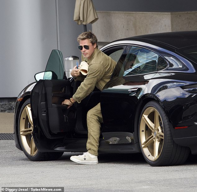 Brad Pitt is seen exiting his new sports car in Los Angeles on Tuesday. The actor recently purchased the $200,000 electric Porsche Taycan which is considered one of the fastest cars on the market