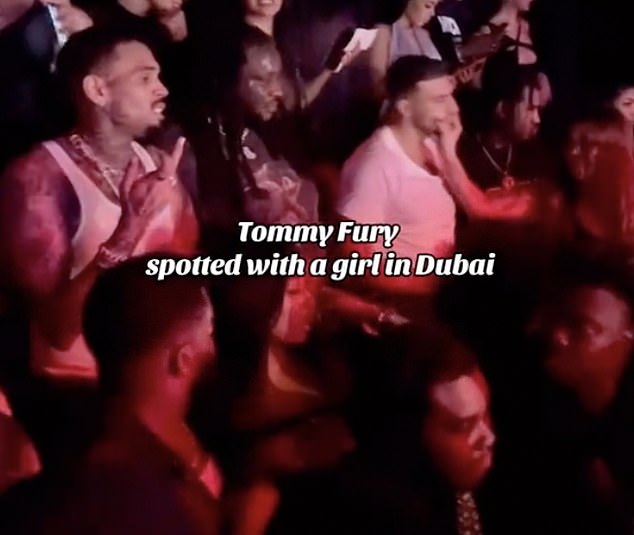 Playful: In video footage shared on TikTok, Tommy Fury (right) is targeted by an attractive brunette - who playfully grabs his face as he dances to her rear - while out with Chris Brown (left)