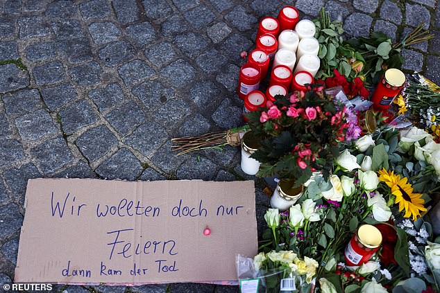 A sign that reads: "We just wanted to celebrate, but then the death came" is placed next to flowers and candles