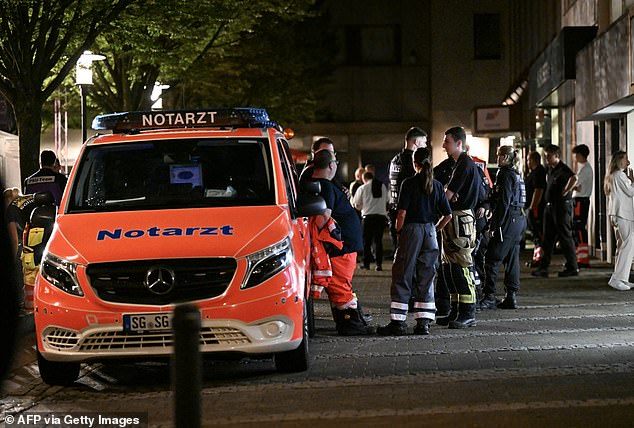 An ambulance and police stand on August 24, 2024 near the scene where at least three people were killed and several injured