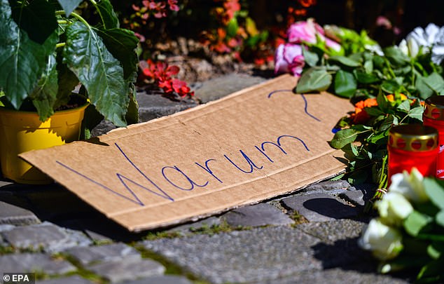 A placard reading 'Why?' among flowers and tributes placed on a sidewalk near the scene after a knife attack, in Solingen, Germany