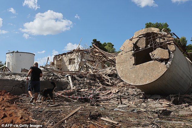 The aftermath of the strike  was clear this morning. Pictured is a man walking with a dog past a the rubble of a destroyed building in Hod HaSharon in the aftermath of an Iranian missile