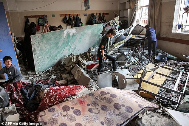 Boys inspect a destroyed classroom in the aftermath of Israeli bombardment on the Palestinian Muscat Governmental School, funded by Omani aid, in Gaza City on October 2