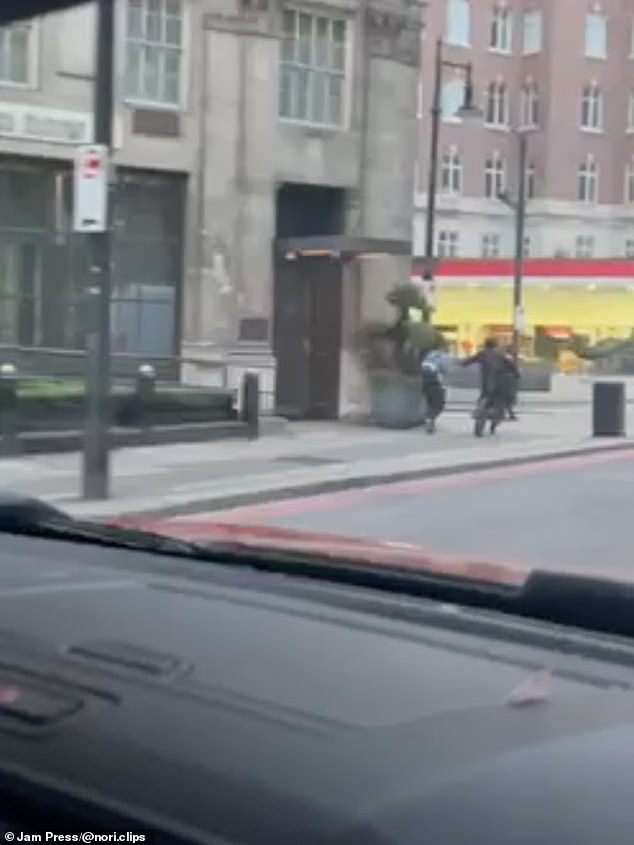 A man has his phone snatched while walking along Park Lane in London's plush West End