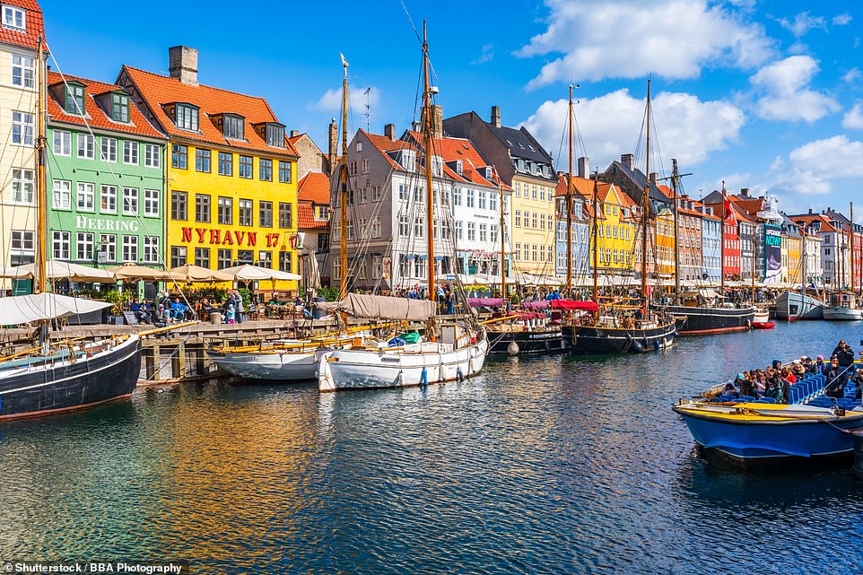 Pictured above is the Nyhavn canal, a popular photo spot in Copenhagen, Denmark. Visit Copenhagen says: 'It doesn't take much more than a few rays of sunshine before Copenhagen's waterfront is filled with renewed energy and joyful faces'