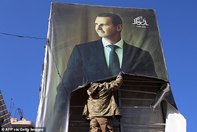 An anti-government fighter tears down a portrait of Syria's President Bashar al-Assad in Aleppo