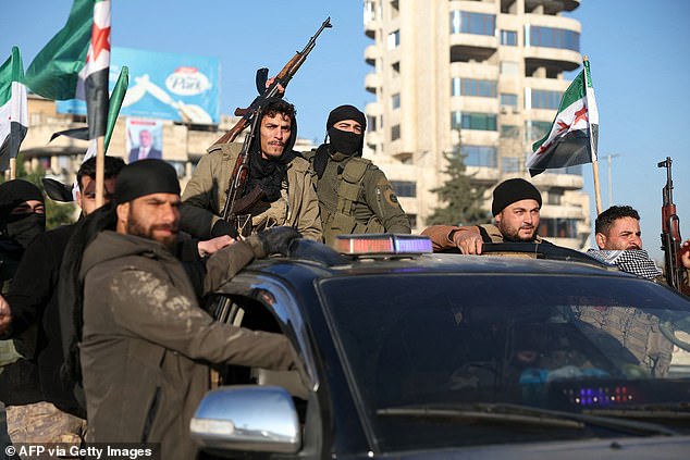 Anti-government fighters brandish their guns as they ride a vehicle in Syria's northern city of Aleppo