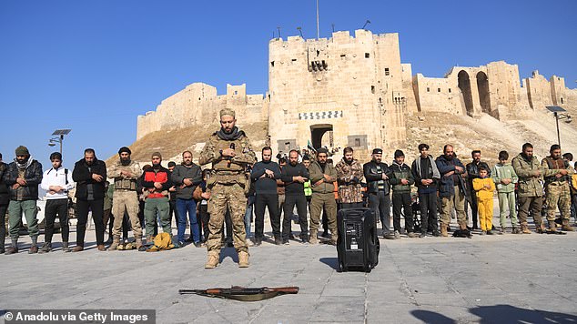 Members of the armed group opposing Syrian President Bashar al-Assad's regime perform Islamic prayer at Aleppo Castle after they seized control of much of Aleppo's city center in Syria