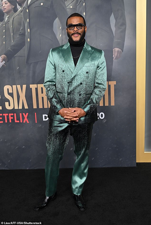 The filmmaker showed off his distinctive style in a metallic green and black suit, with a black turtleneck underneath