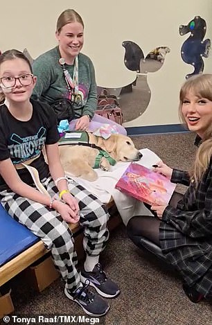 Swift laughs at the camera as she signs some memorabilia for a young girl