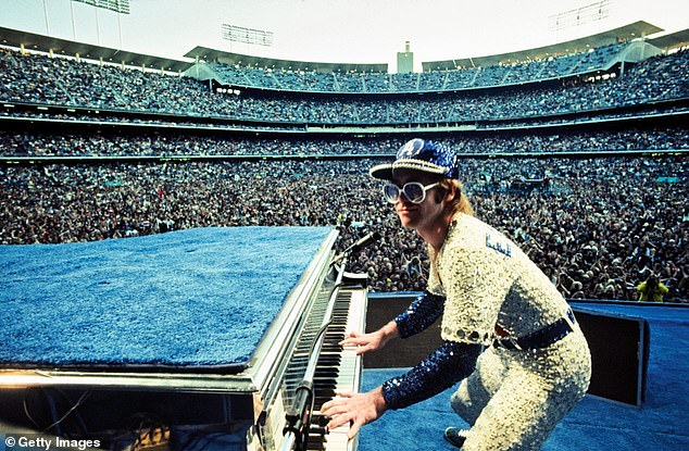 The statute features the iconic musician as he defies gravity as and is suspended mid-air over his rhinestone piano in his signature handstand move from the era (Elton pictured 1975)