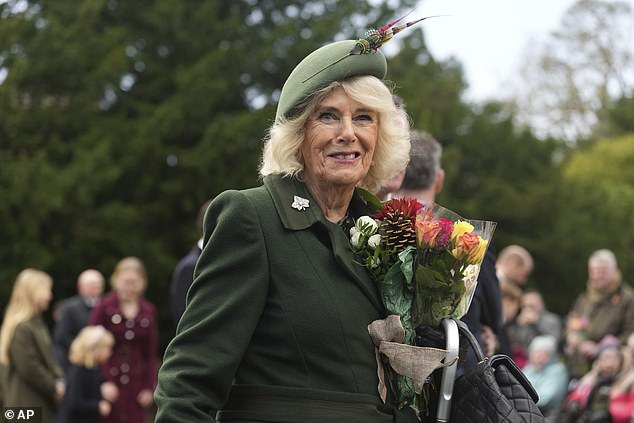 Queen Camilla smiles as she holds a bouquet of flowers given by well-wishers after attending the Christmas day service