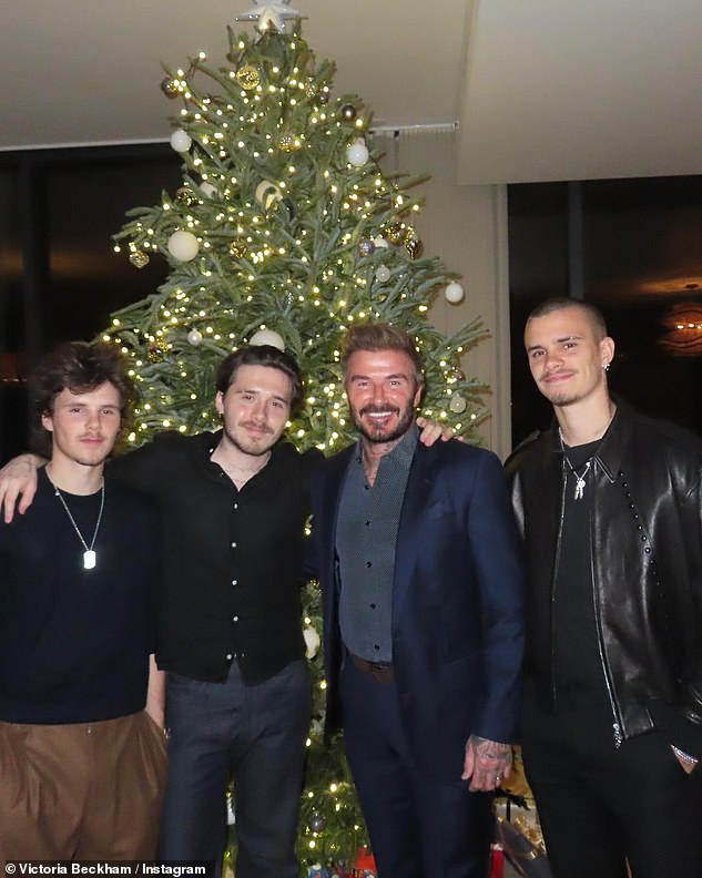 Former England ace David looked dapper in a navy suit as he posed with his three sons