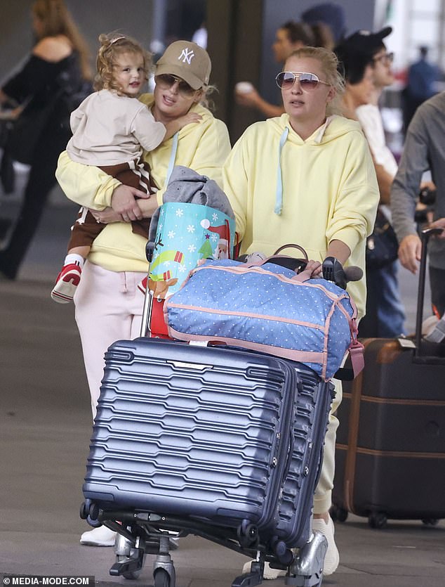 She finished her travel ensemble with a pair of white and fluorescent orange sneakers and a light brown New York Yankees baseball cap