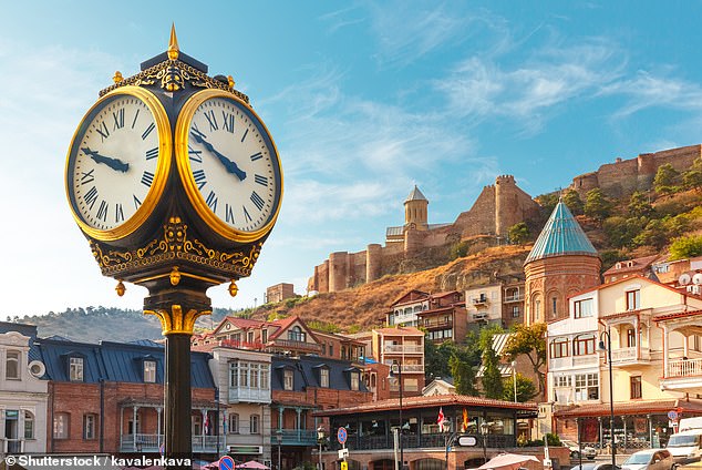 The city clock in Old Meidan Square over shadowed by Narikala ancient fortress in Tbilisi