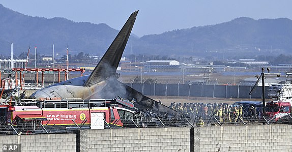 Firefighters and rescue team members work on the runway of Muan International Airport in Muan, South Korea, Sunday, Dec. 29, 2024. (Lee Young-ju/Newsis via AP)