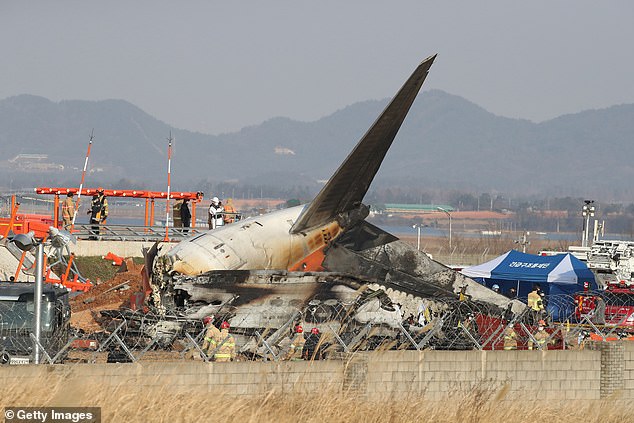 Firefighters and rescue team work at the wreckage of a passenger plane at Muan International Airport