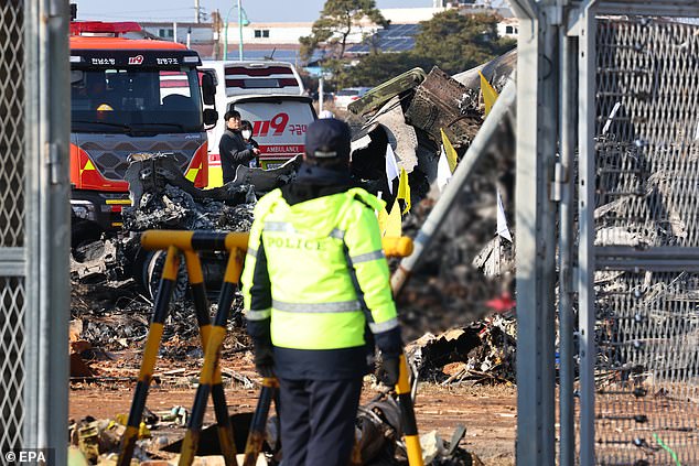 Firefighters carry out rescue operations at Muan International Airport with the wreckage seen in the background