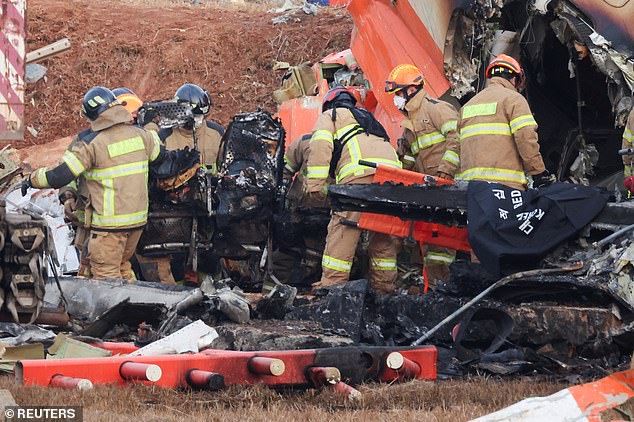 Firefighters carry burnt chairs from the deadly aircraft crash at Muan International Airport - December 29, 2024