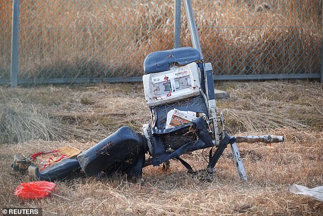 A chair from the wreckage sits alone on the grass with a newspaper seen on the seat