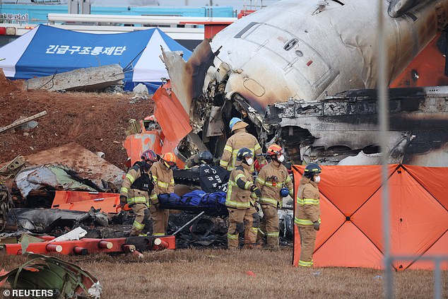 Firefighters carry the body of a passenger from the wreckage. At least 125 people have been killed