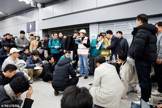 People listen at Muan International Airport as an official discloses the additional names of passengers who died in the horror plane crash