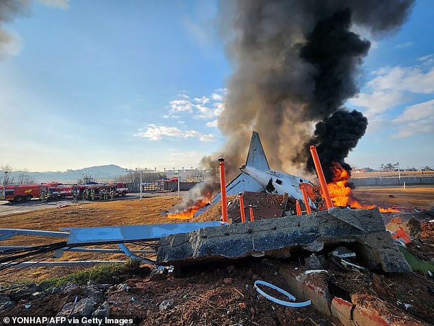 Fire and smoke rise from the tail section of a Jeju Air Boeing 737-800 series aircraft after the plane crashed and burst into flames at Muan International Airport